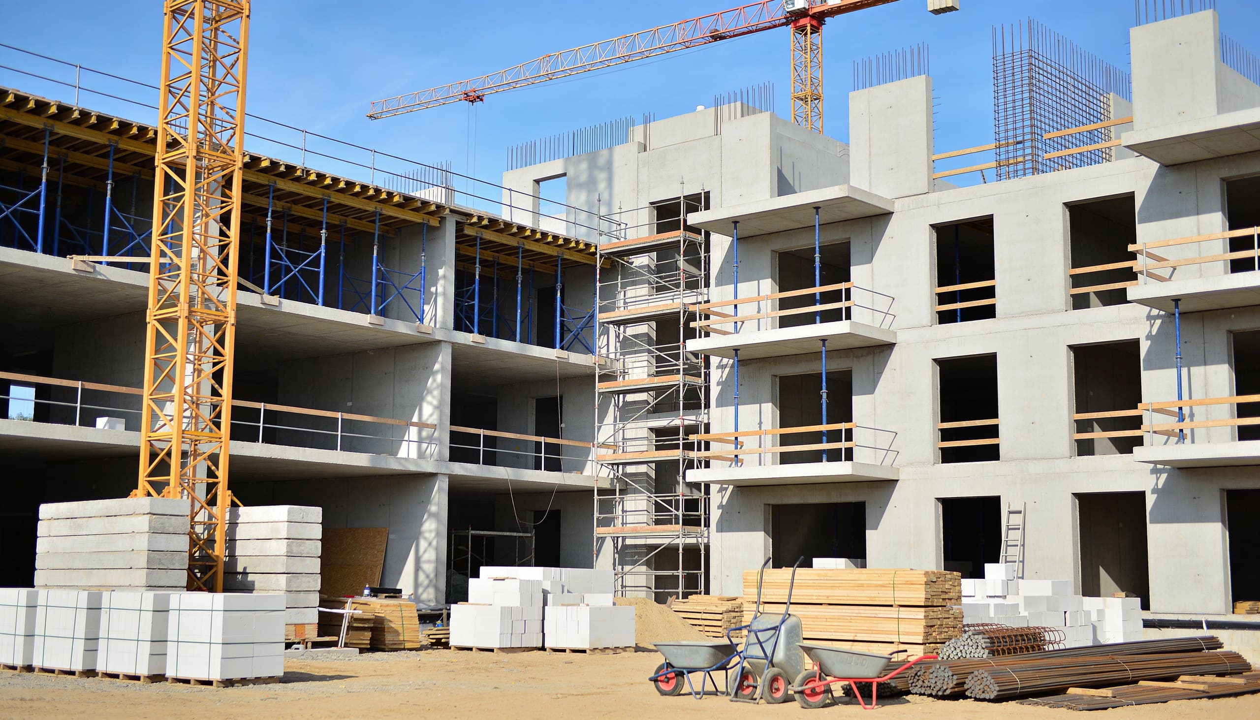 Concrete structure rising behind site scaffolding and a tower crane
